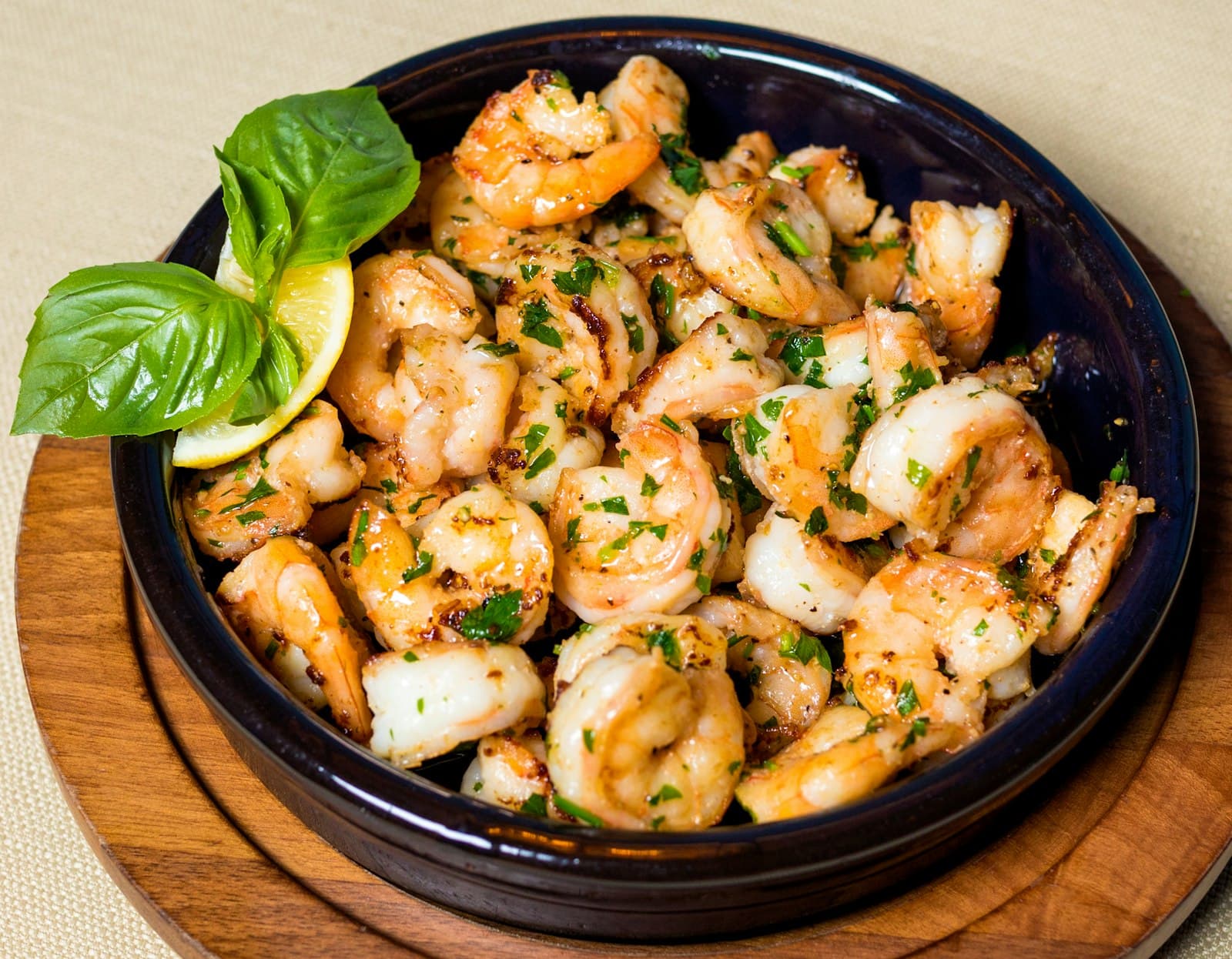 Bowl of grilled prawns tossed in garlic and herbs with lemon
